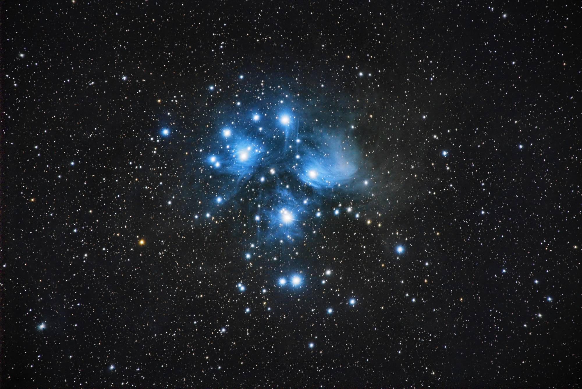 A blue cluster of stars in a night sky