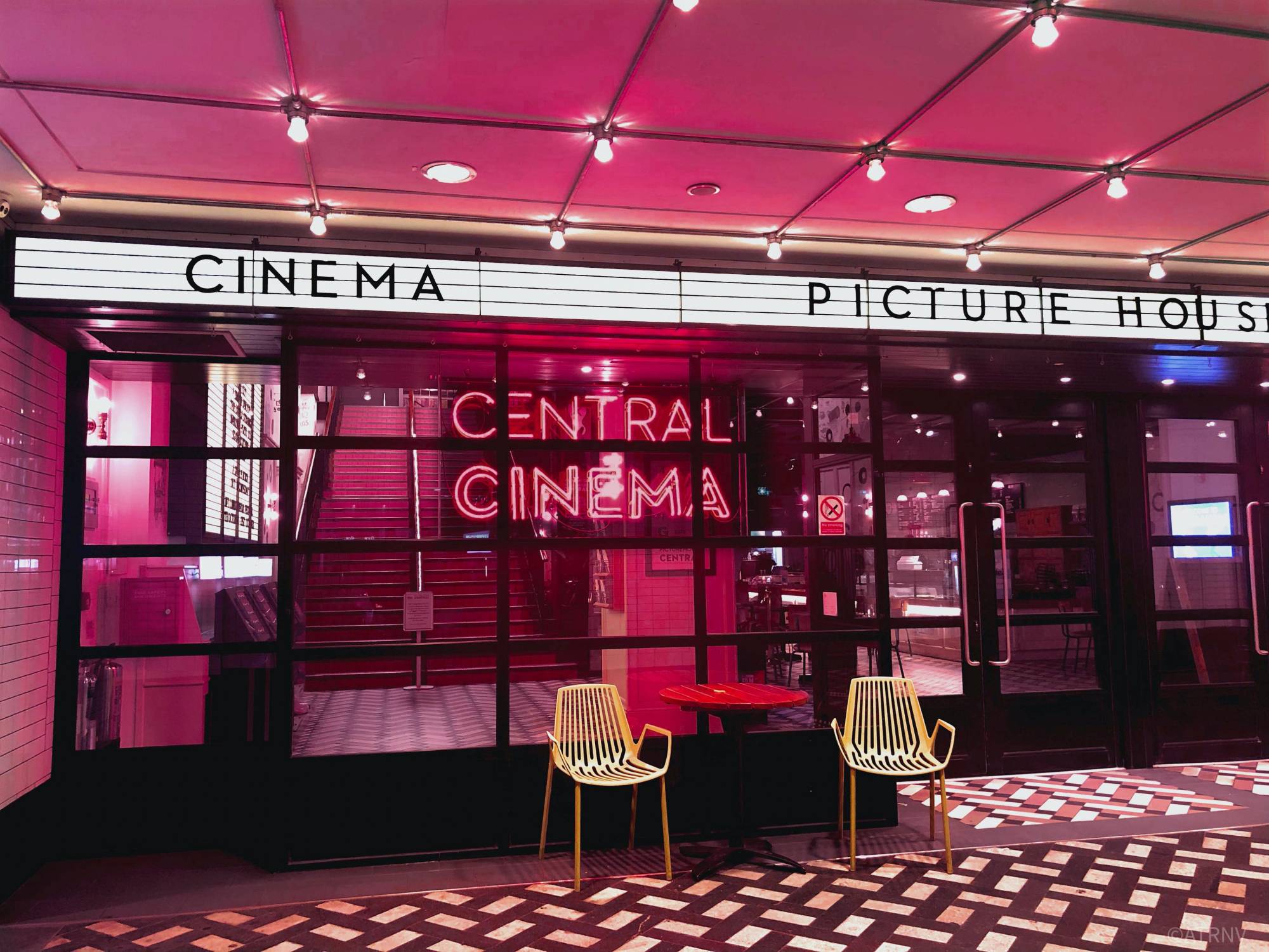 The front of a movie theater bathed in crimson light, as seen from the front doorway.