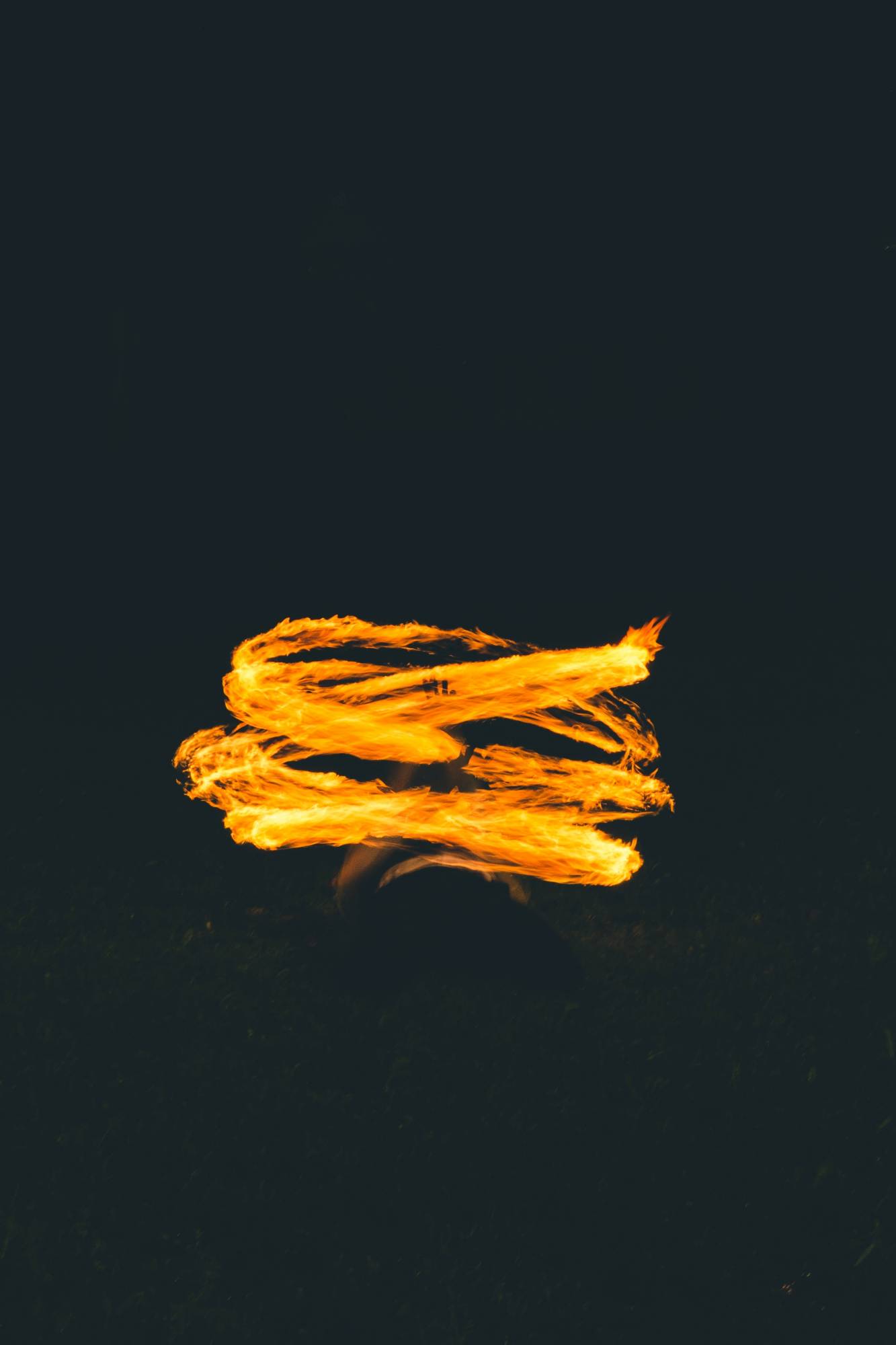 A artistic, flowing yellow, gold flame against a deep black background.