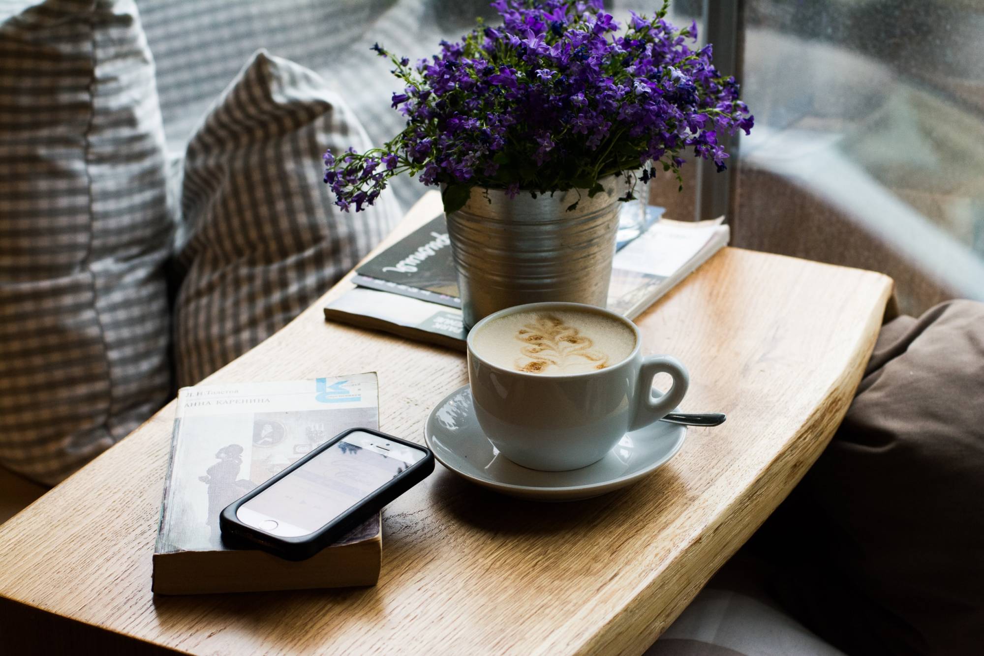 A coffee table with a book, phone and cup of coffee