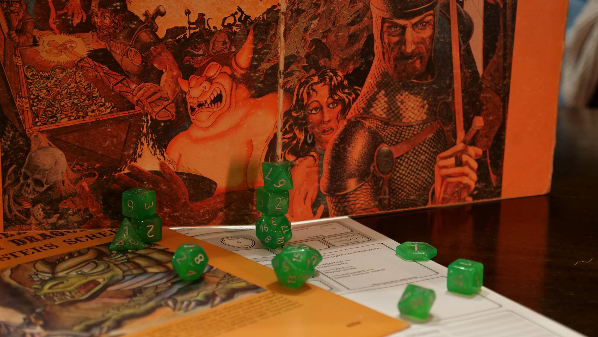 Green dice stacked against a Dungeons and Dragons Second Edition Dungeon Master screen. The screen has the image of adventurers discovering treasure alongside a demon.