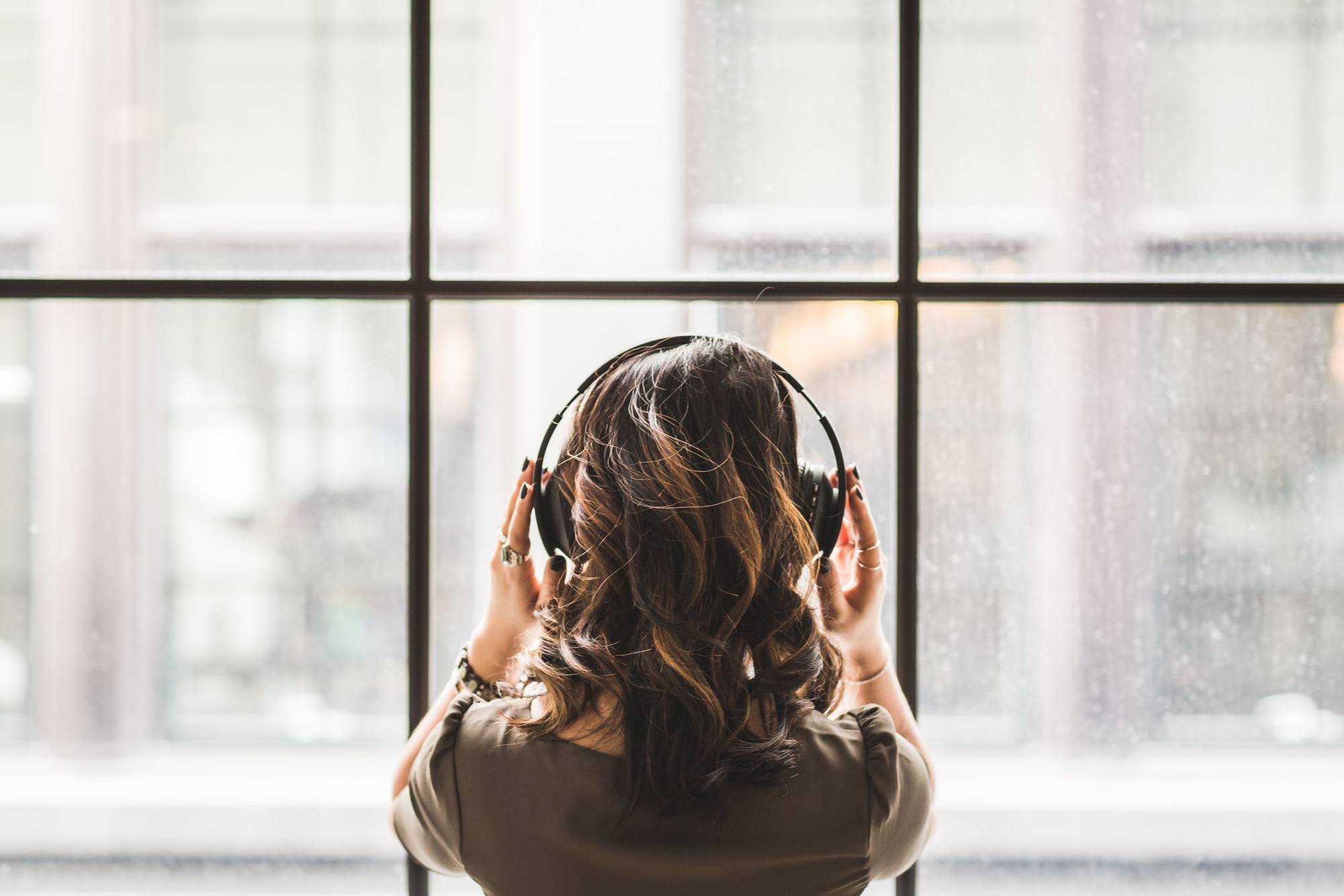 Photo of a woman staring out the window with headphones on
