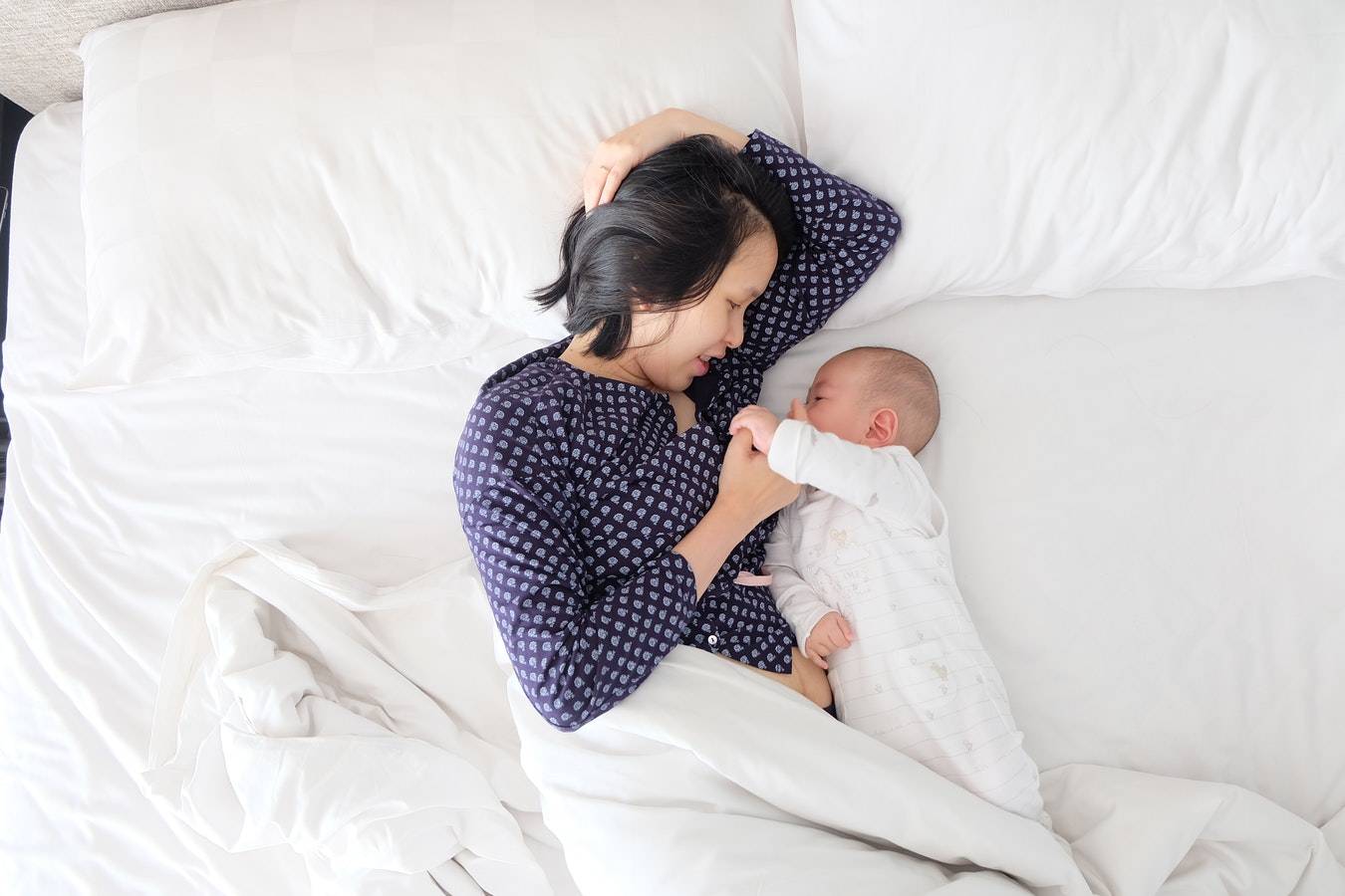 mother snuggles up to her baby in bed