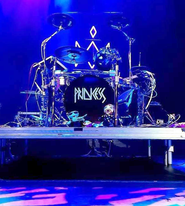 Photo of drum set in a nightclub with the word Princess on it and a few plushies in front.