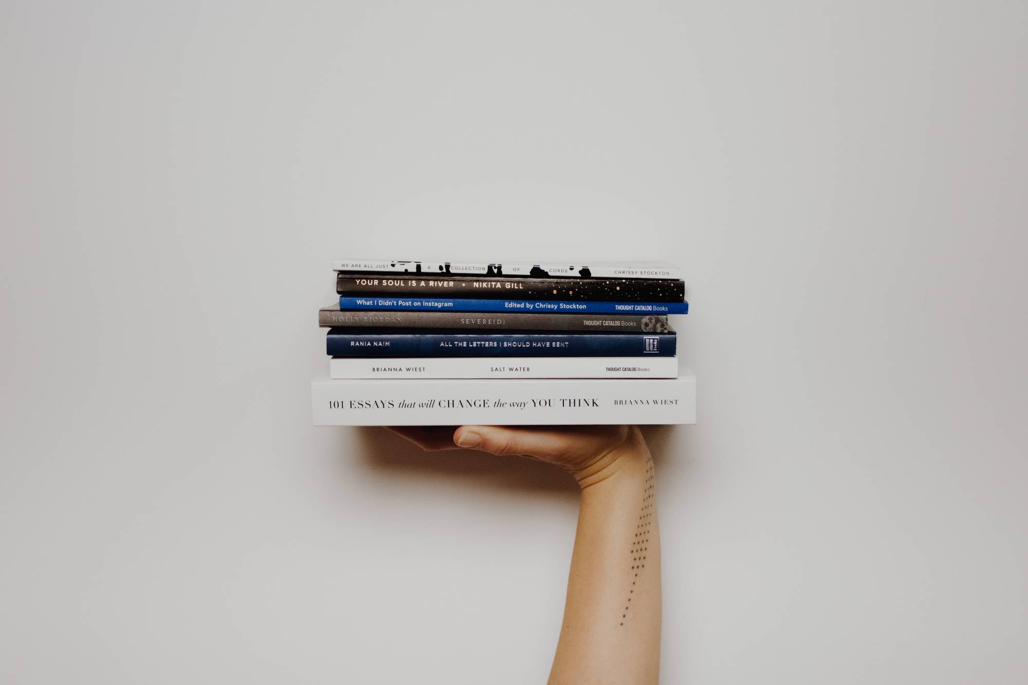 Photo of a person holding up a stack of books