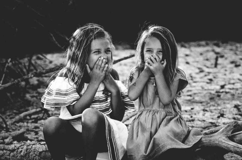 A black and white photo of two young girls laughing.