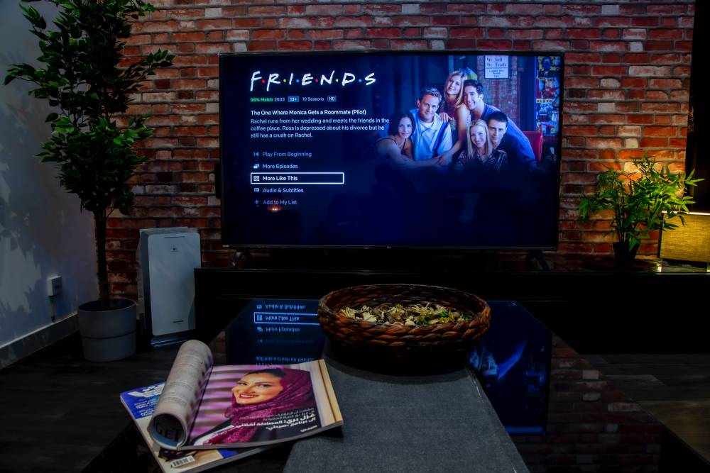 A black flat screen TV turned on to "Friends" in a living room