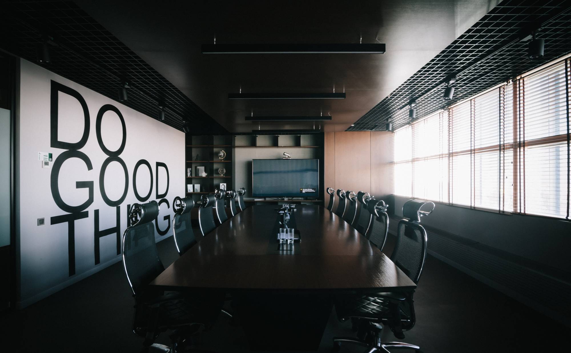 A board room with a central table and the words "Do Good Things" written on the wall.
