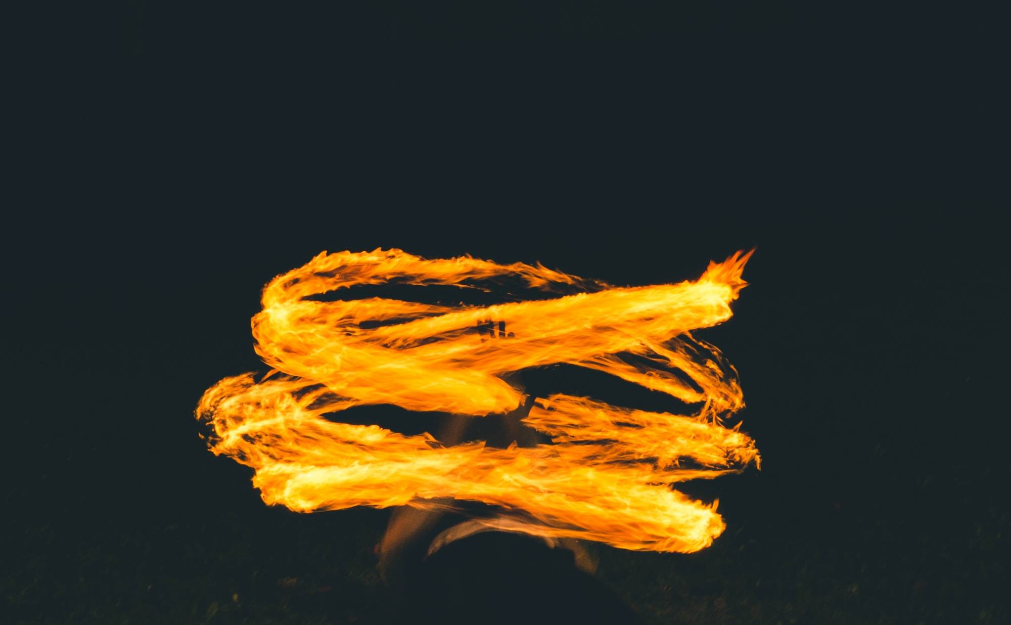 A artistic, flowing yellow, gold flame against a deep black background.
