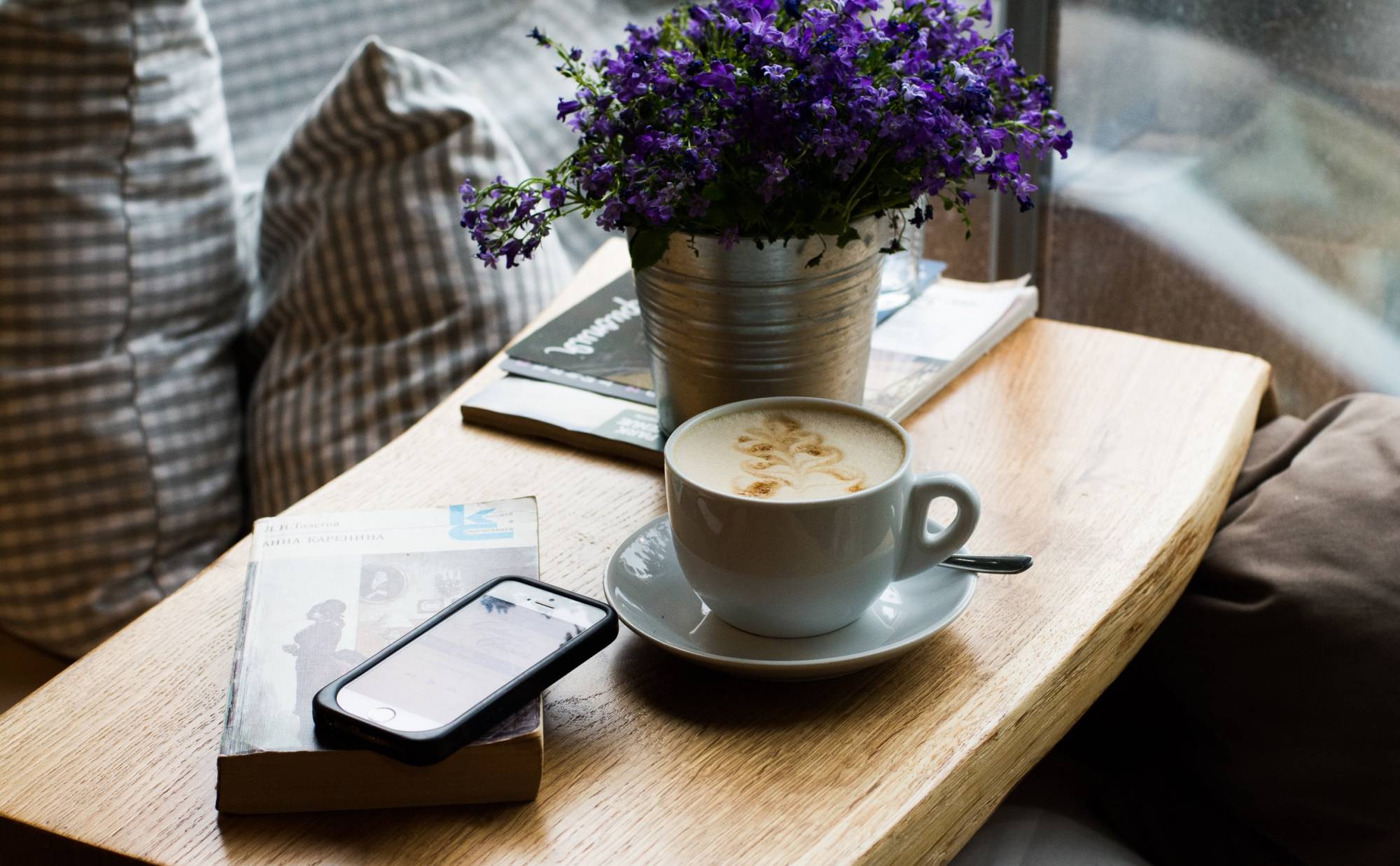 A coffee table with a book, phone and cup of coffee