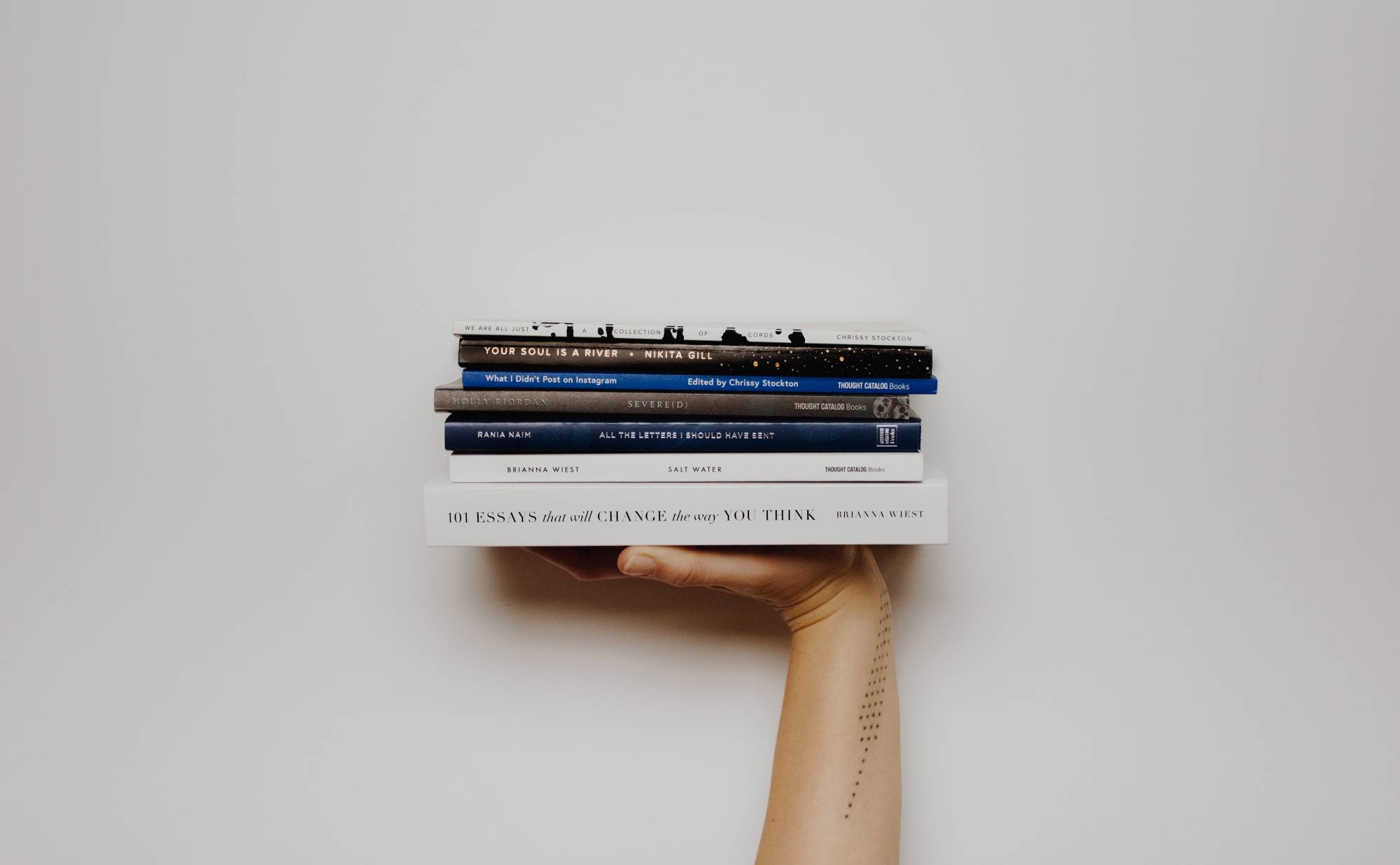 Photo of a person holding up a stack of books