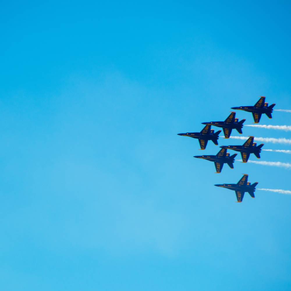 Six jet planes fly across the sky in a triangular formation.