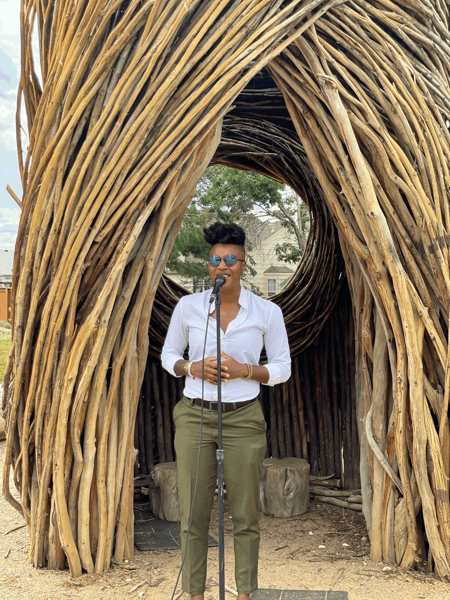 Kerrie Joy stands in front of a microphone in front of the Spirit Nest in Anythink Wright Farms.